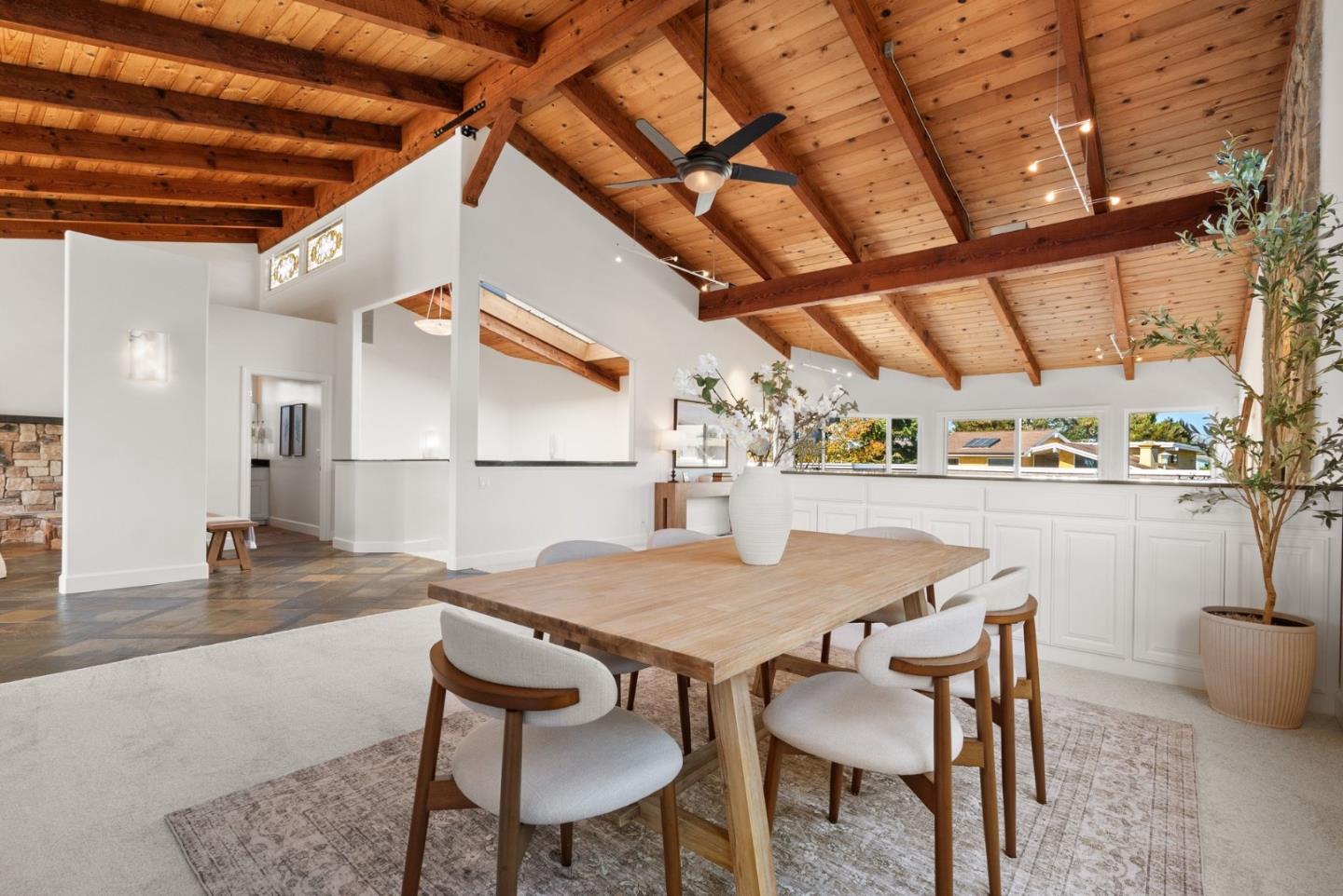 Dining area with a long wooden table beneath a vaulted exposed-beam ceiling.
