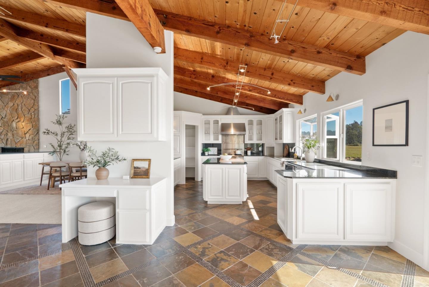Kitchen with white cabinets, a large island, and a vaulted exposed-wood ceiling.