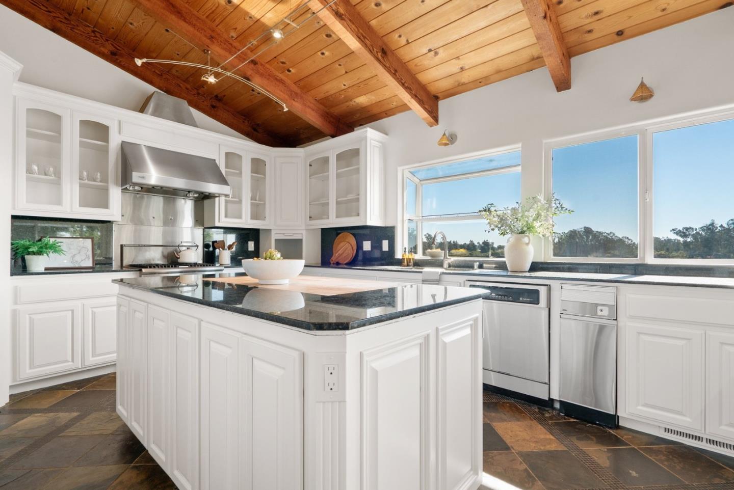 Kitchen with a central island, white cabinets, stainless appliances, and a vaulted wood ceiling.