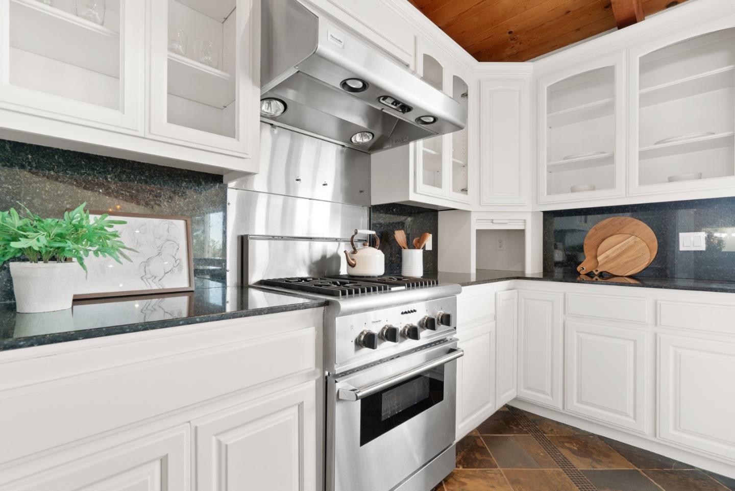 Kitchen with white cabinetry, stainless steel range and hood, dark stone counters, and a wood-plank ceiling.