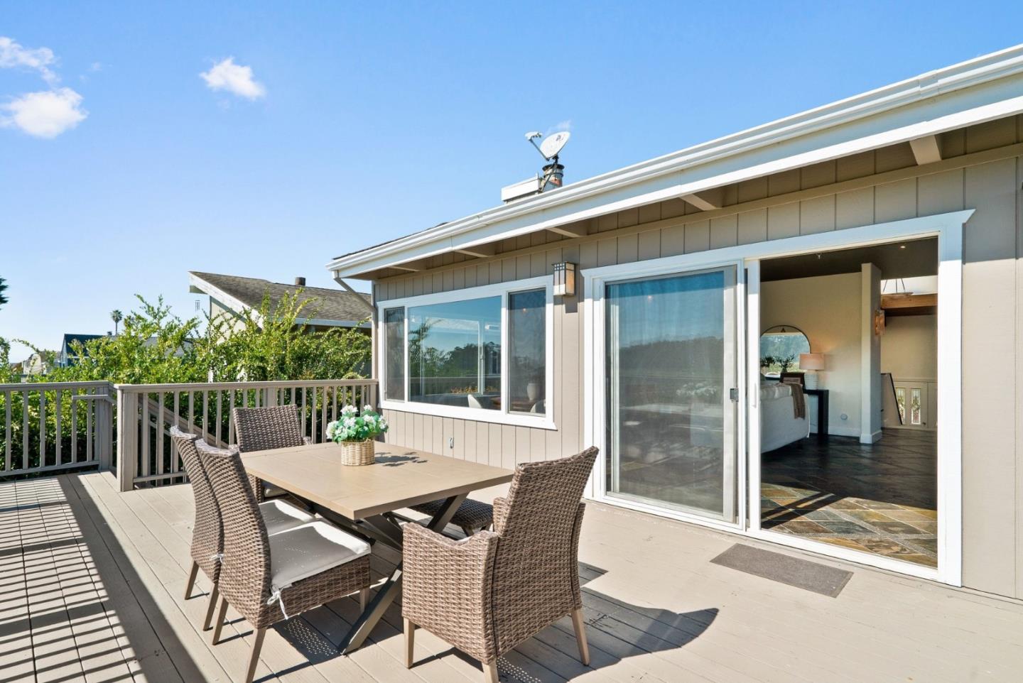 Home deck with wicker dining set beside open sliding doors to the living room