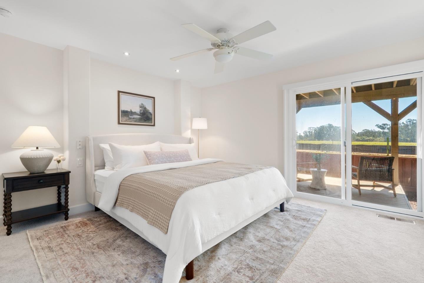 Furnished bedroom with a white bed and sliding doors opening to a covered patio.