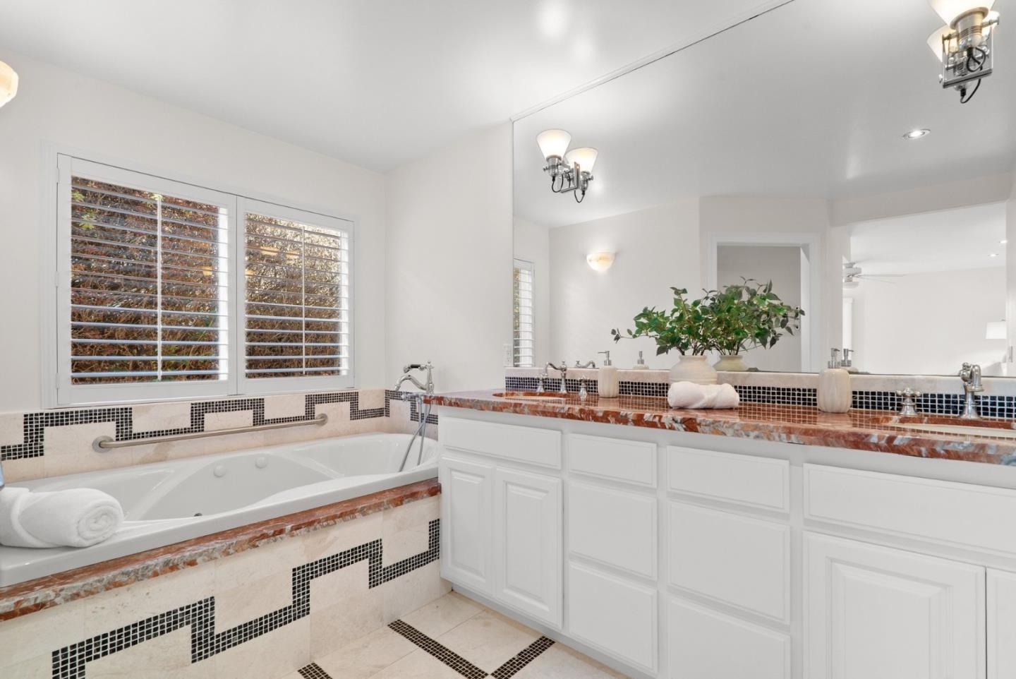 Bathroom with a soaking tub, white double vanity, and black-and-white mosaic tile accents.