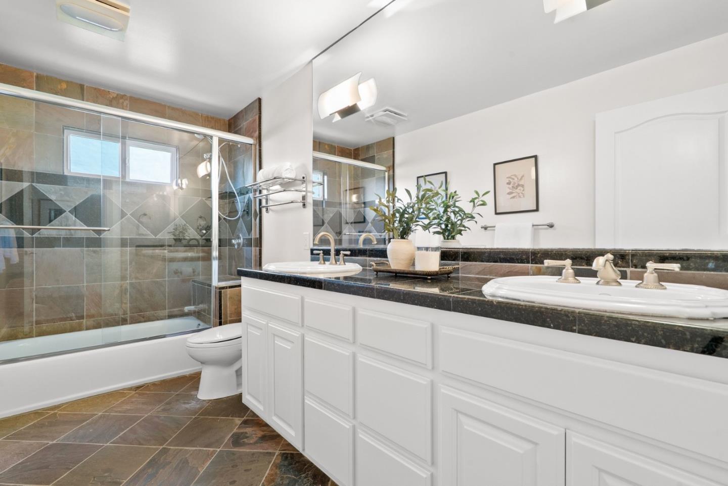 Bathroom with a long double vanity and a glass-enclosed tiled tub and shower.
