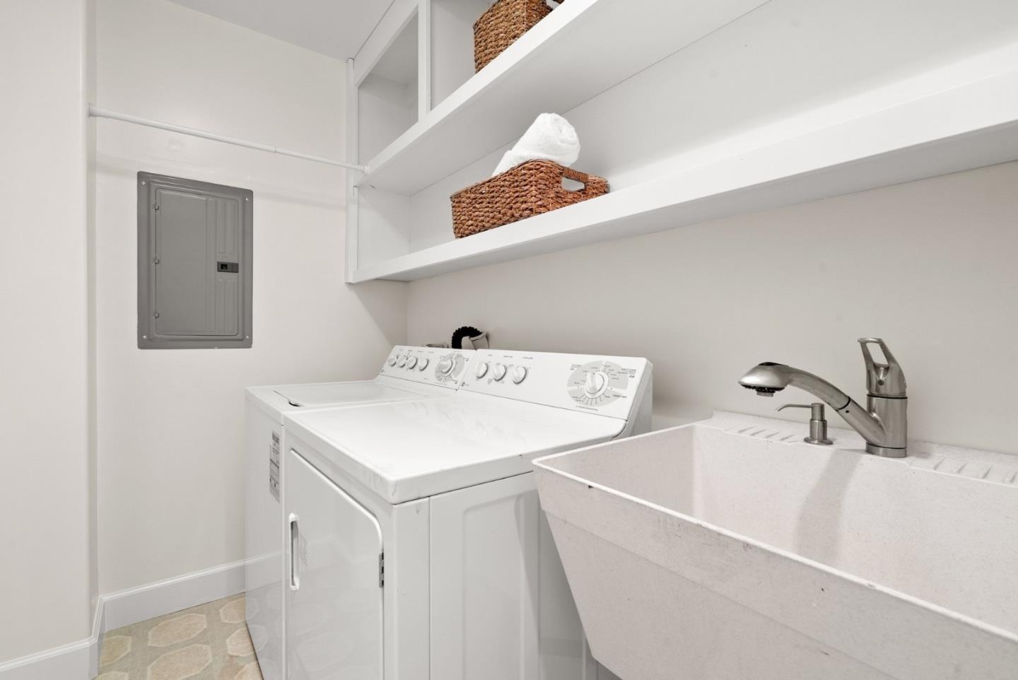 Laundry room with a white washer and dryer, deep utility sink, and built-in shelves.