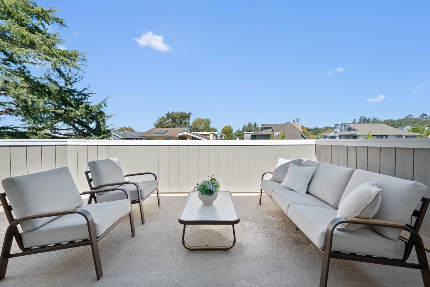 Furnished terrace with cushioned seating and a coffee table overlooking nearby homes.