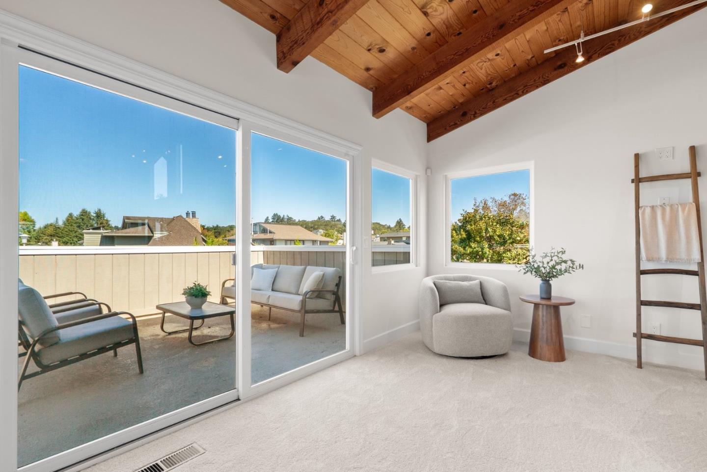 Bright living area with exposed wood beams and sliding doors to a furnished balcony.