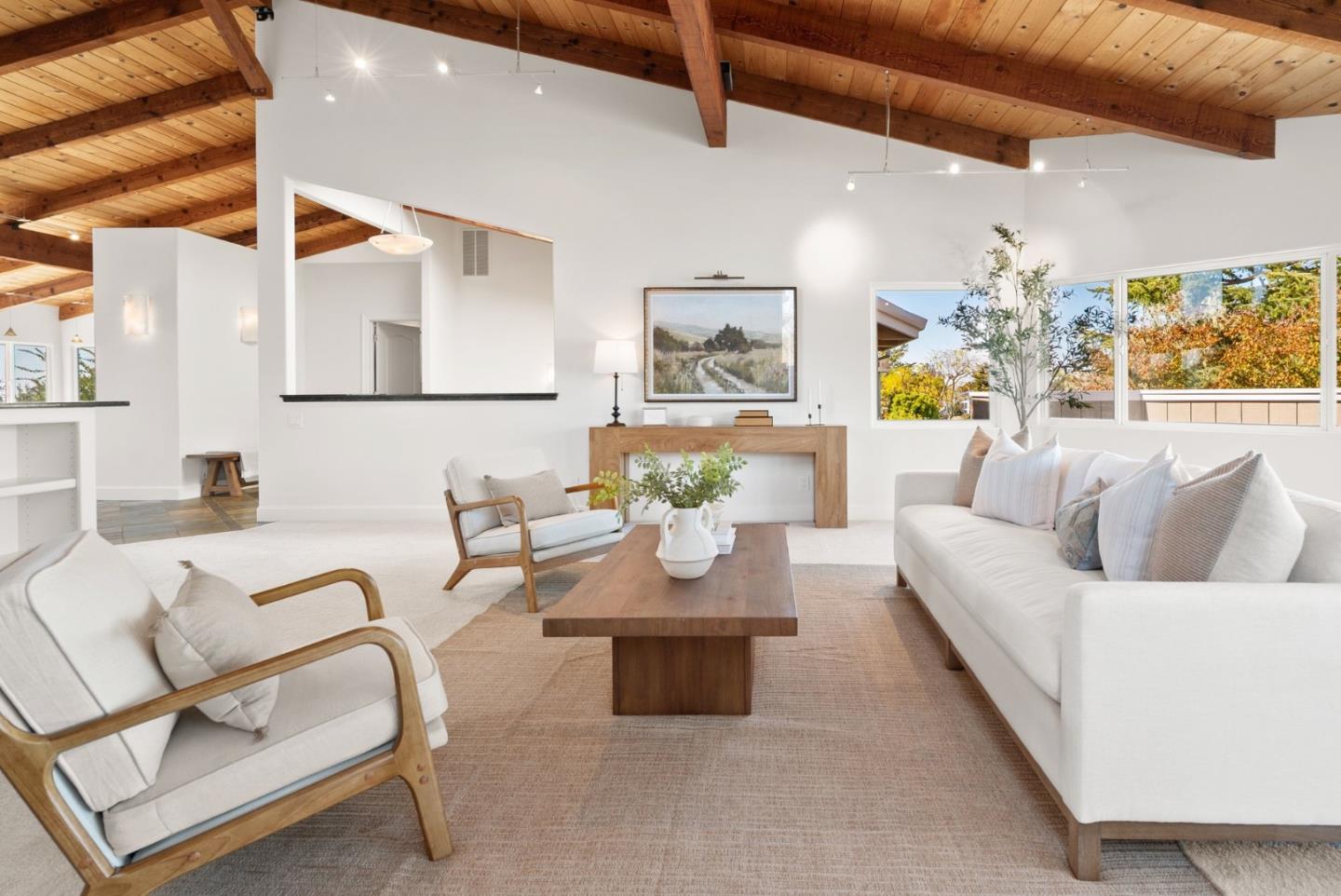 Living room with white sofas, wood-framed chairs, and exposed wooden ceiling beams.