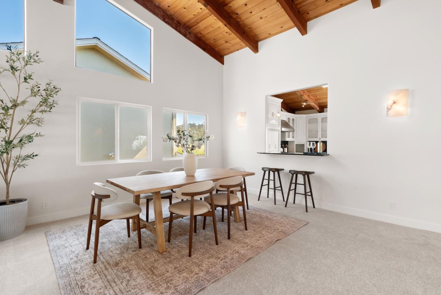 Dining area with a vaulted wood ceiling, a long table, and a pass-through to the kitchen.