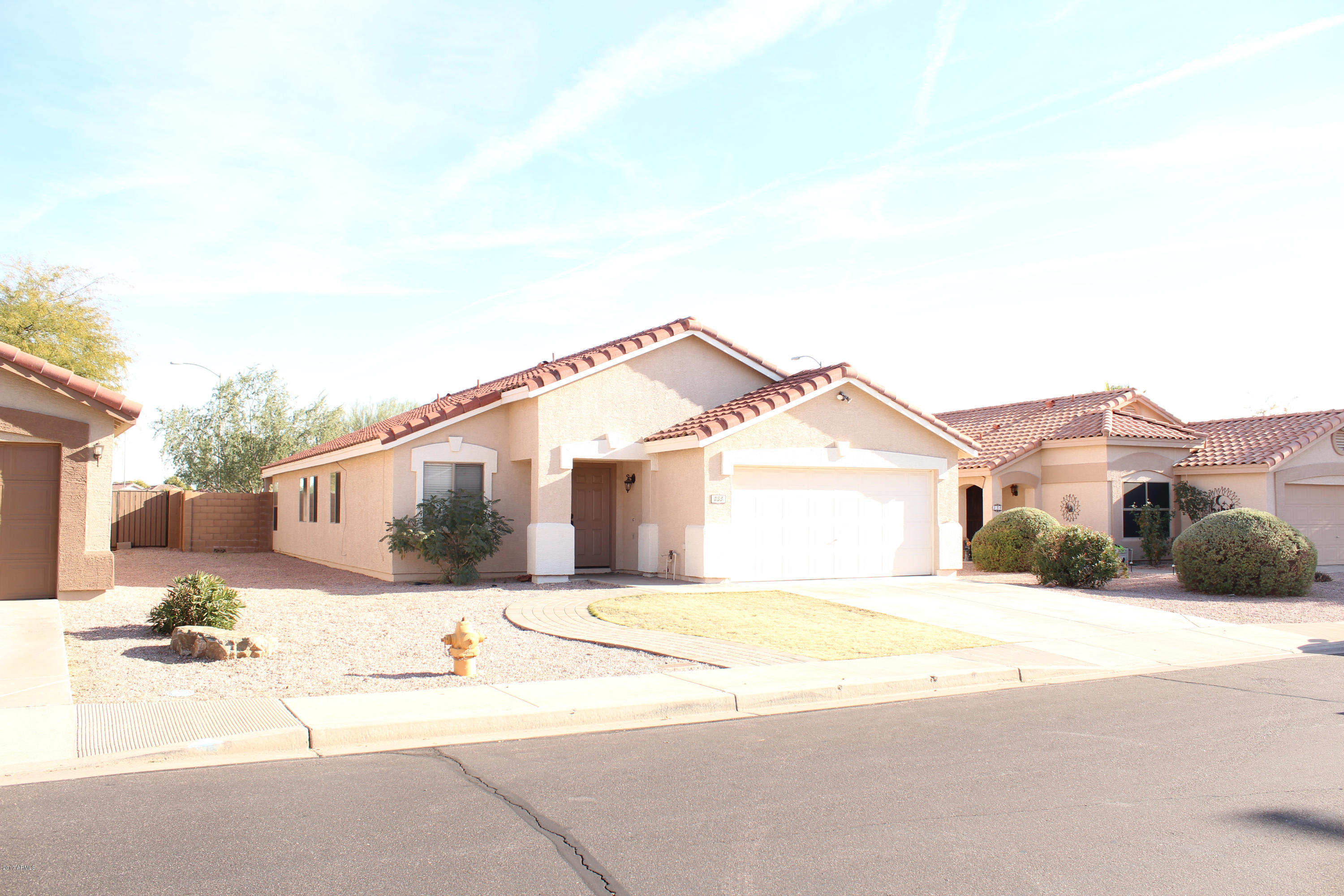 Single-story stucco home with a red tile roof, two-car garage, and gravel landscaping.