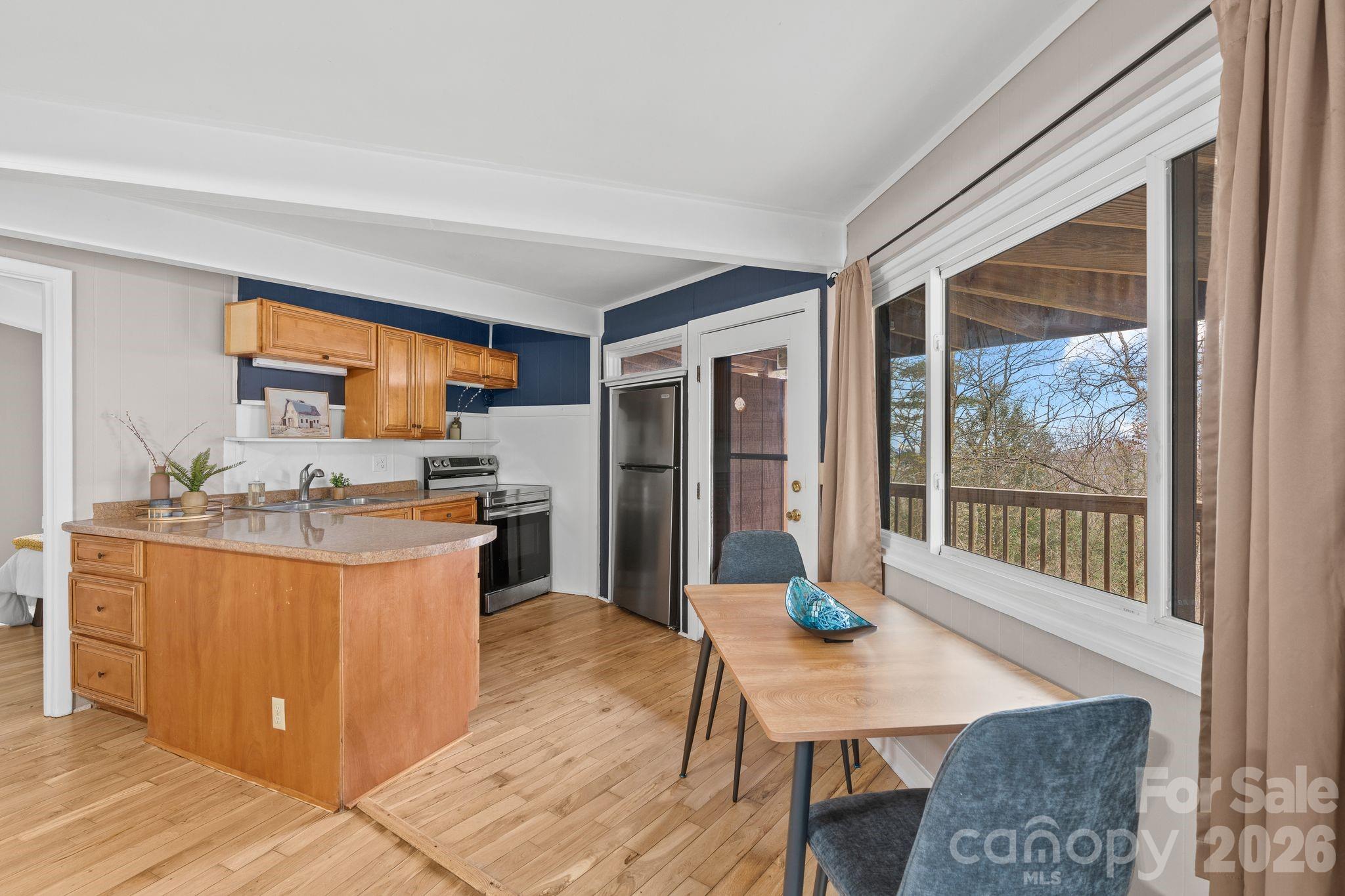 Kitchen and dining area with a wood island and cabinetry beside a large window overlooking a deck.