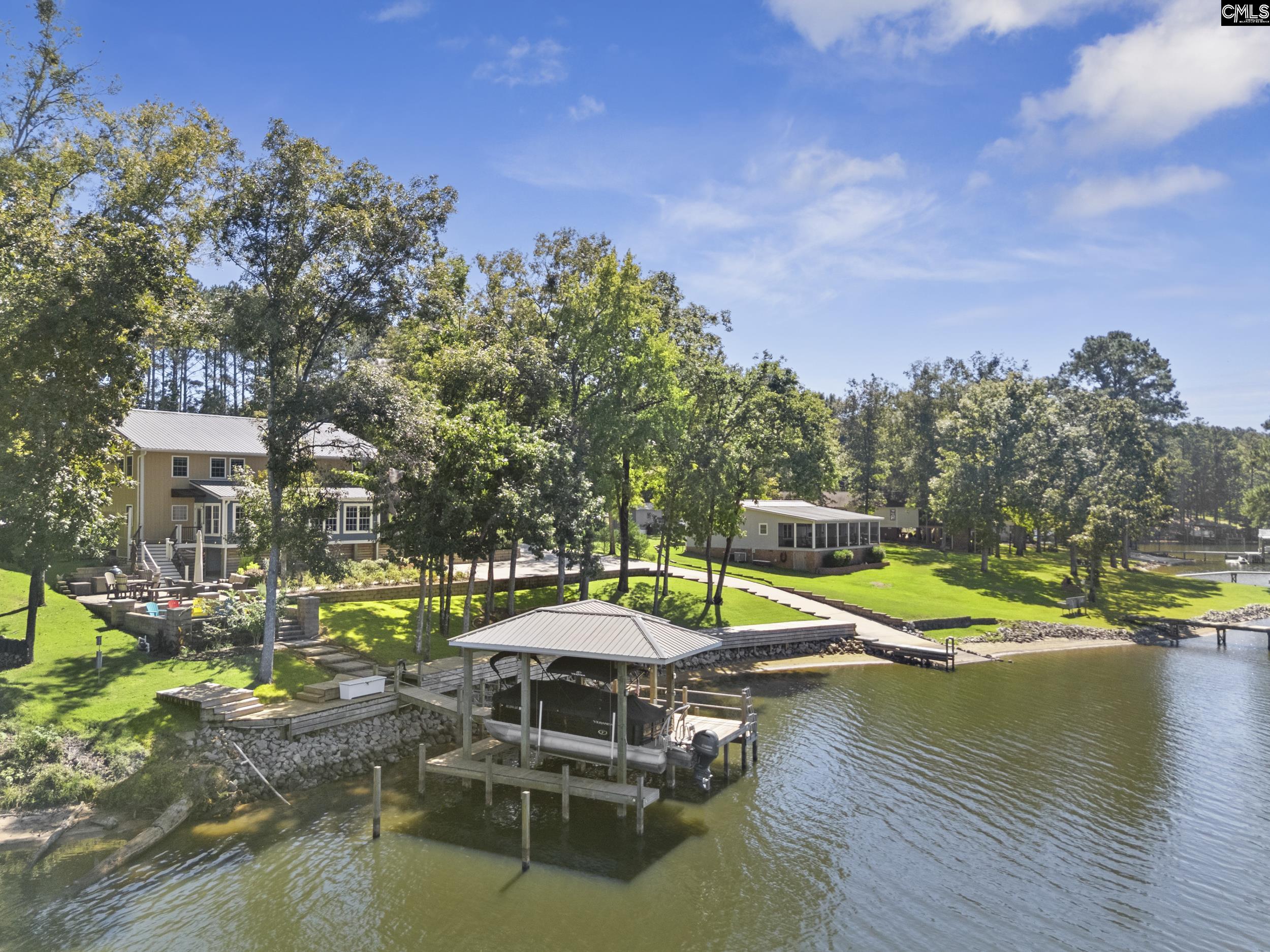 Waterfront homes with wooded lawns, docks, and a covered boat slip on the lake.