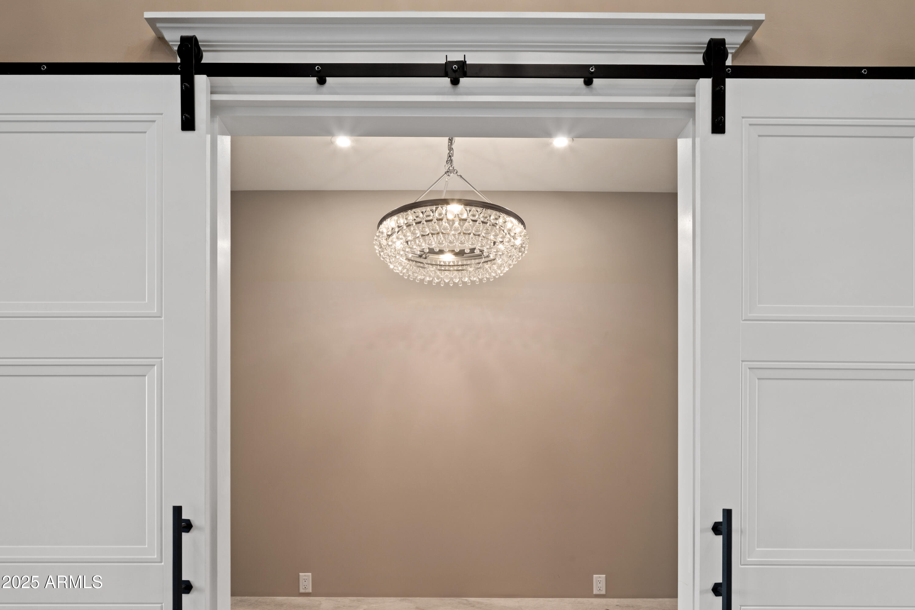 Crystal chandelier framed by white sliding barn doors with black hardware.