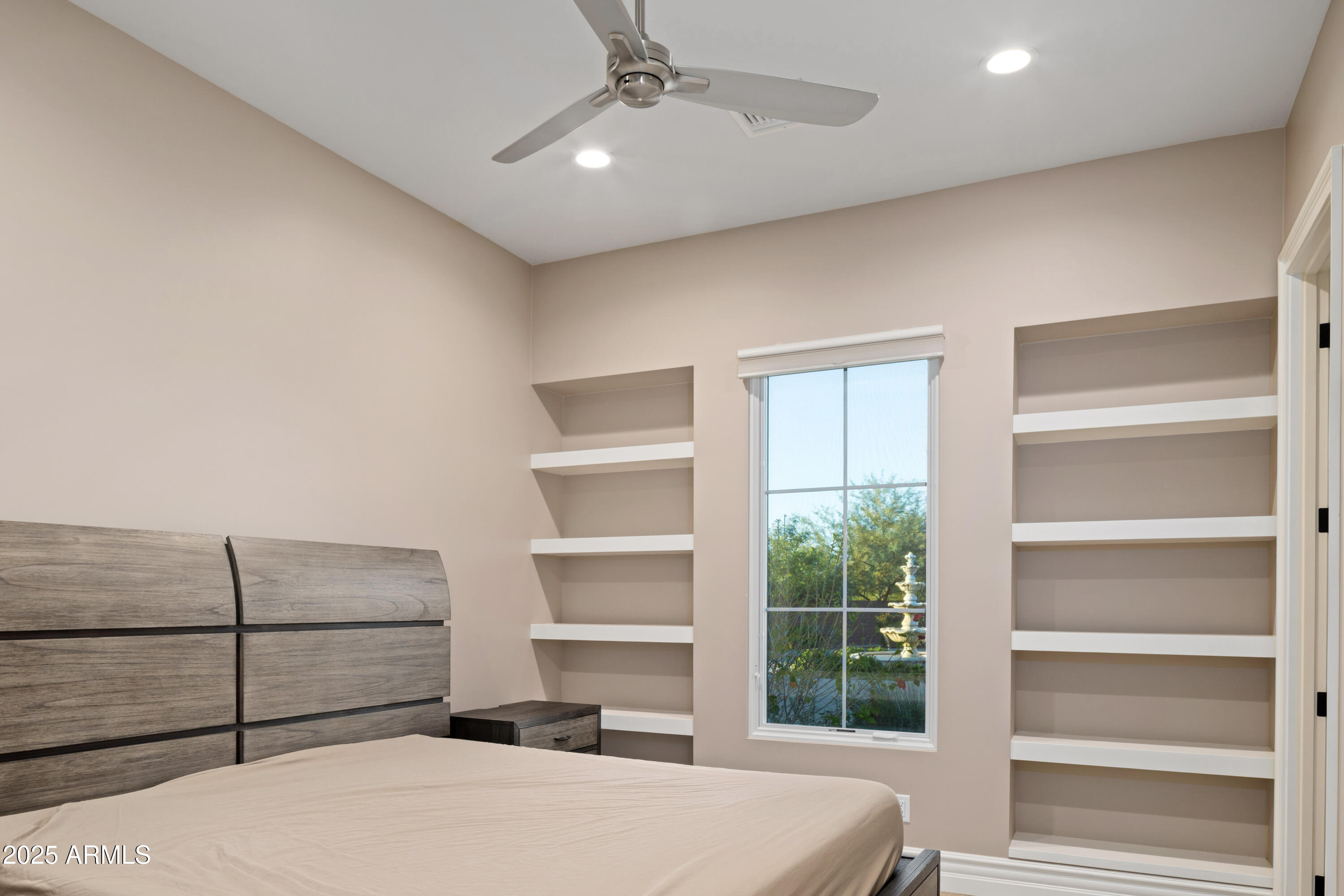 Bedroom with built-in open shelves flanking a window and a ceiling fan.