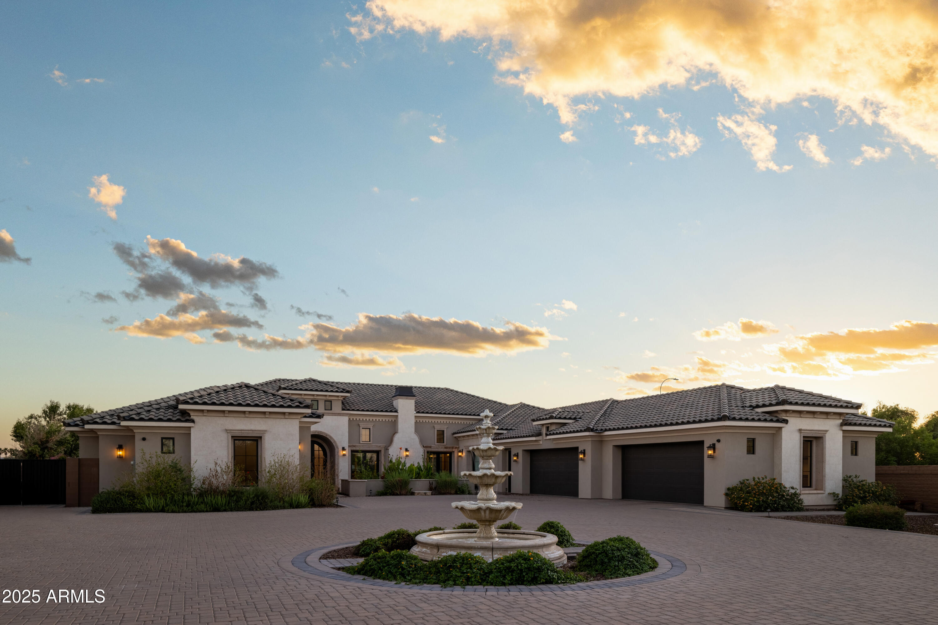 1011 E Kingbird Place home with courtyard fountain and wide paved drive at sunset.