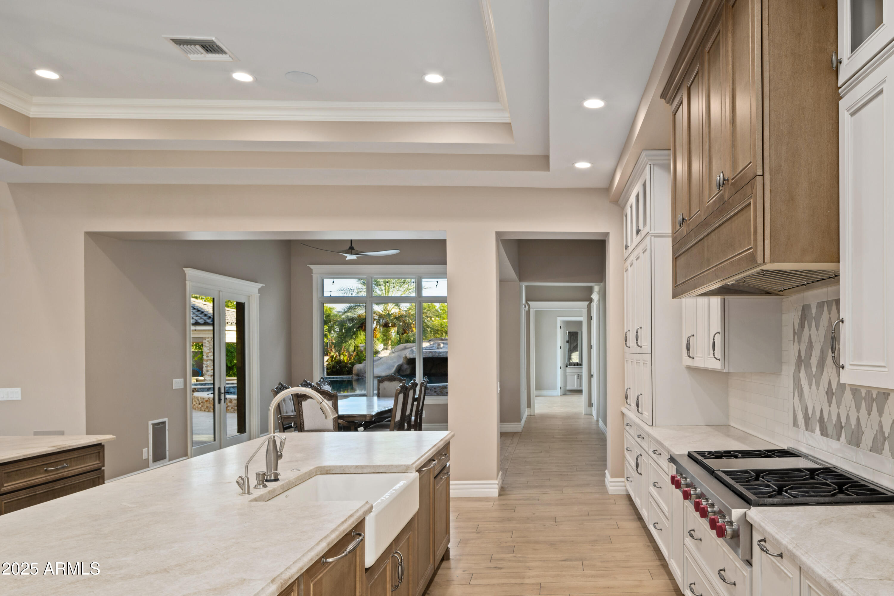 Kitchen with a large stone island, wood range hood, and dining area opening to the backyard.