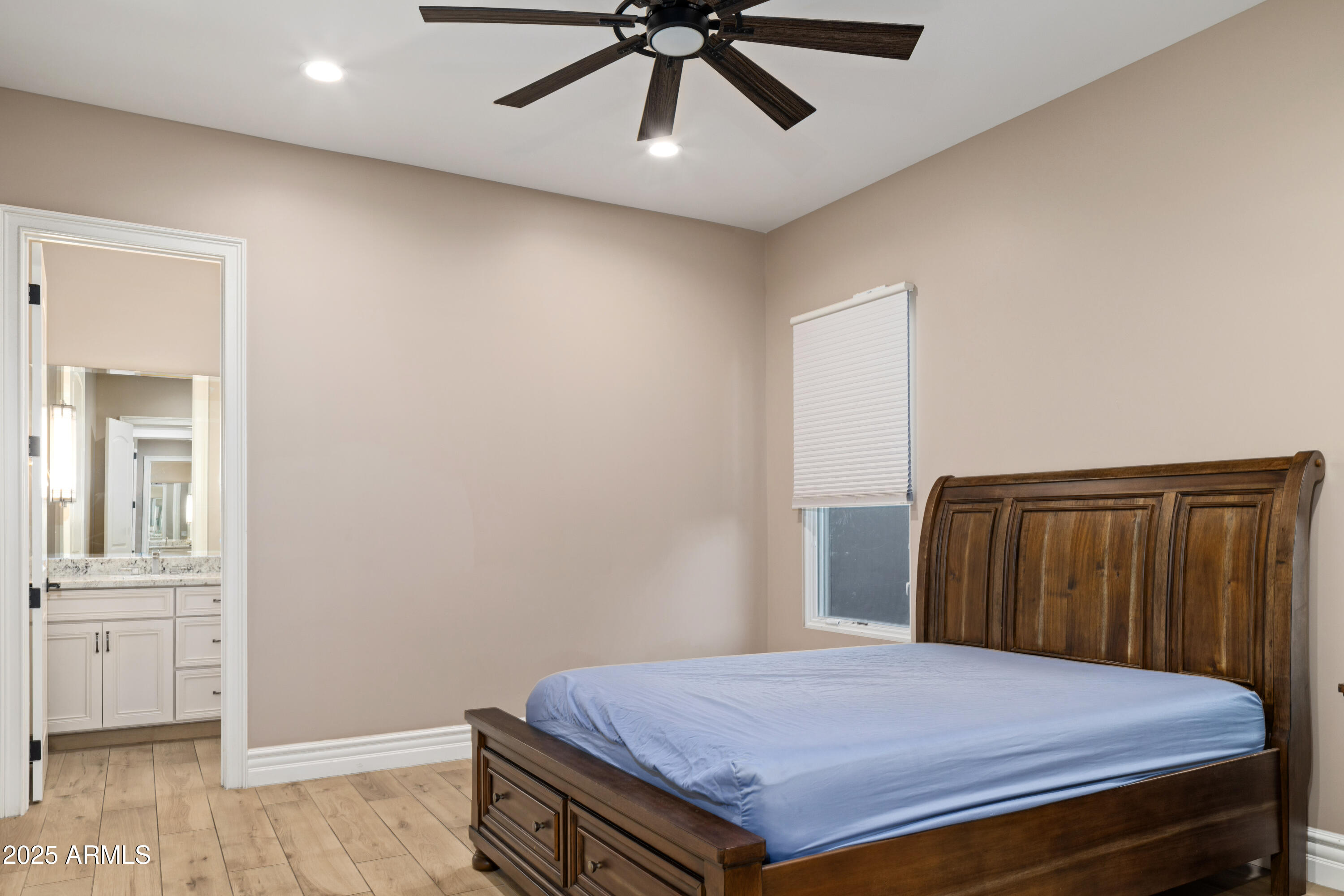Bedroom with a dark wood bed, blue mattress, ceiling fan, and doorway to an adjoining bathroom.