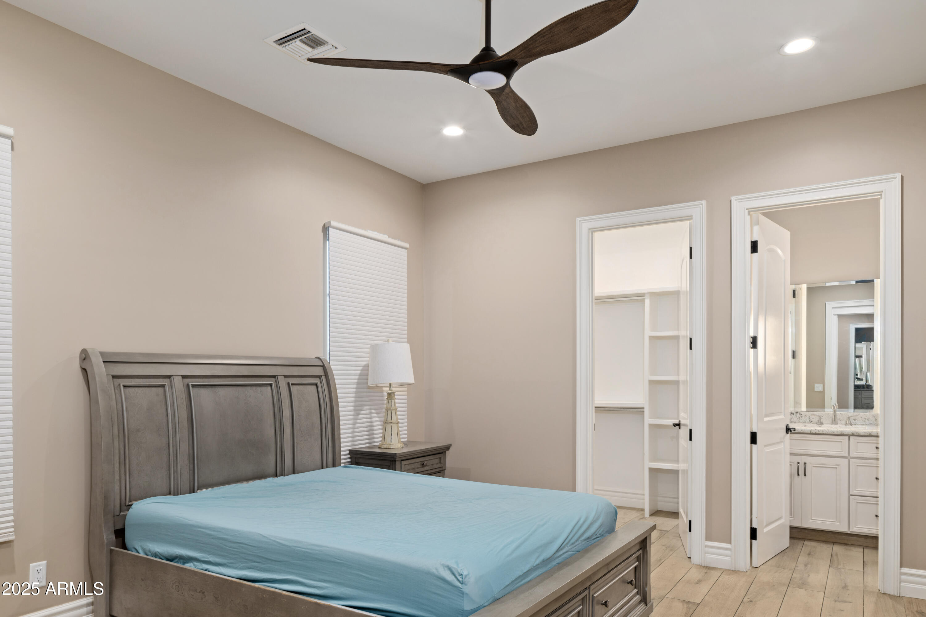 Bedroom with blue bedding, a dark wood ceiling fan, and ensuite bathroom access.