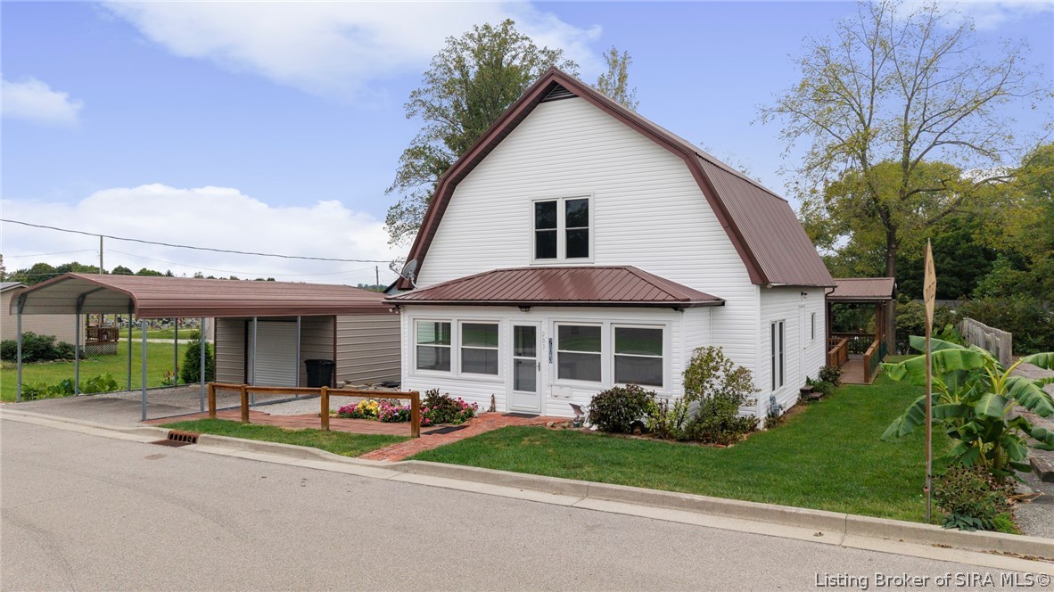 White two-story house with a steep brown metal roof and attached carport.