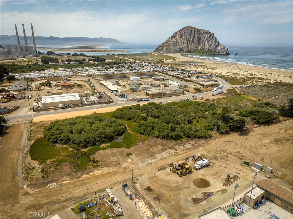 Graded coastal parcel with construction equipment, Morro Rock, beach, and ocean in the distance.