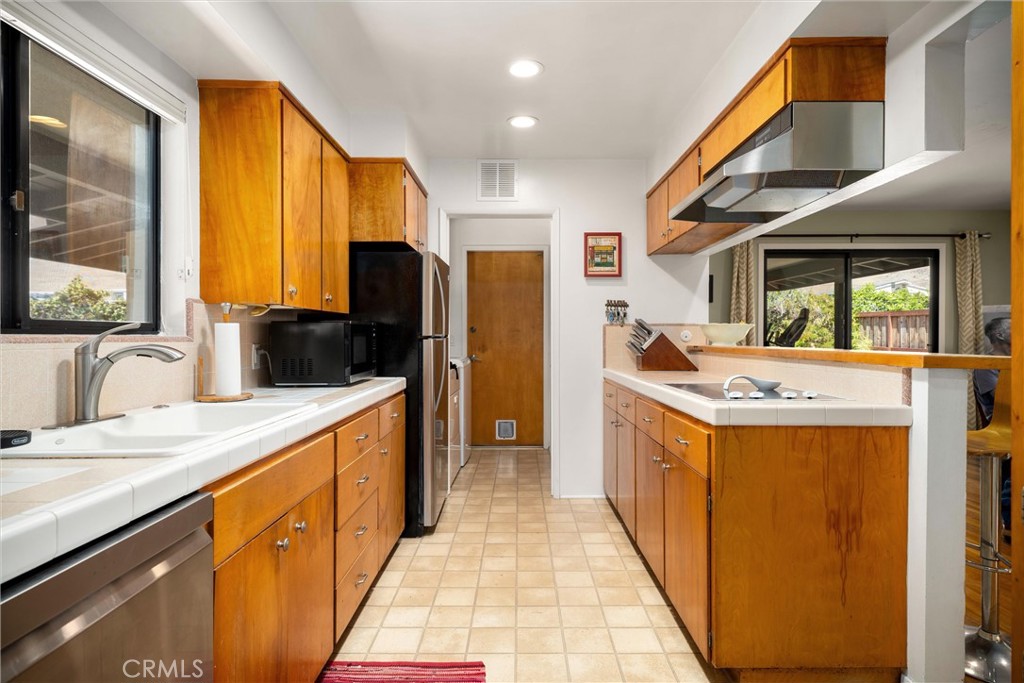 Galley kitchen with honey-colored cabinets, white counters, and a pass-through to the adjoining room.