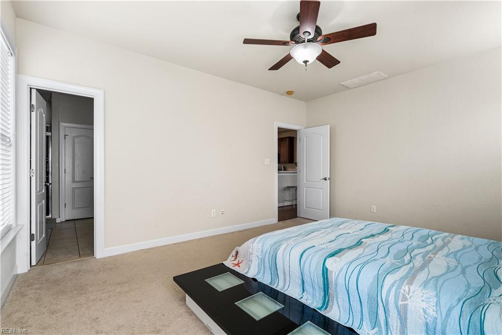 Bedroom with a blue-and-white patterned bedspread, dark bedside table, and ceiling fan.