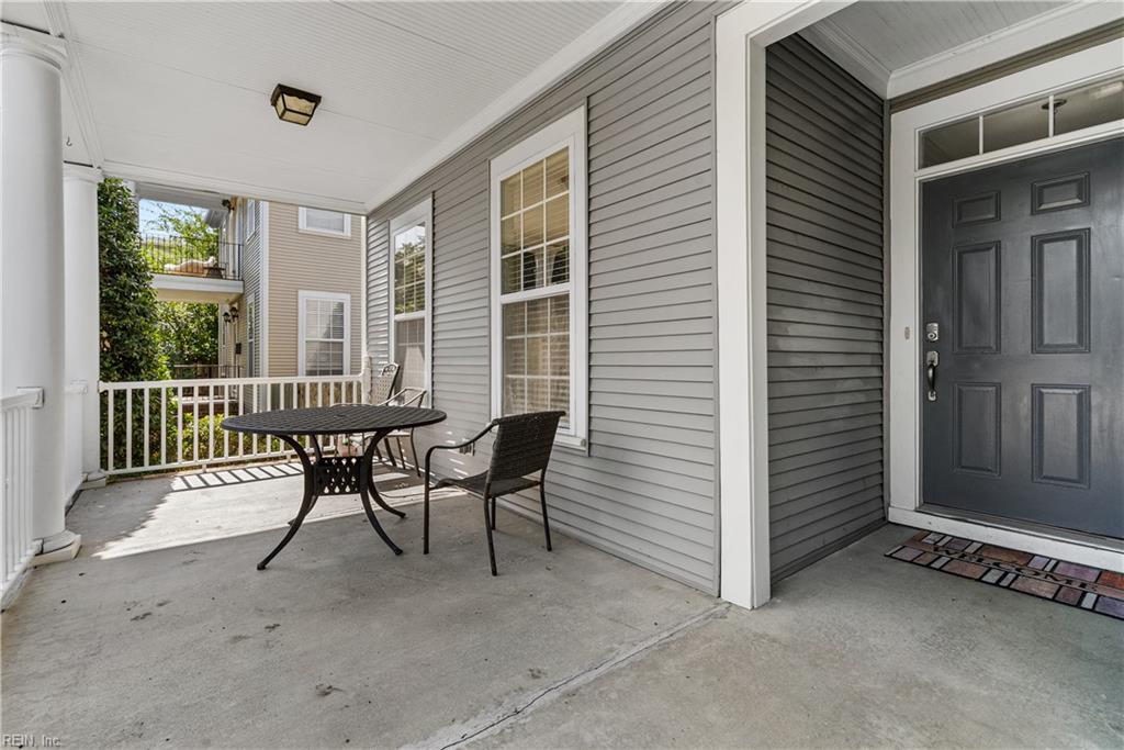 Covered front porch with a dark entry door, white railing, and black patio table and chairs.