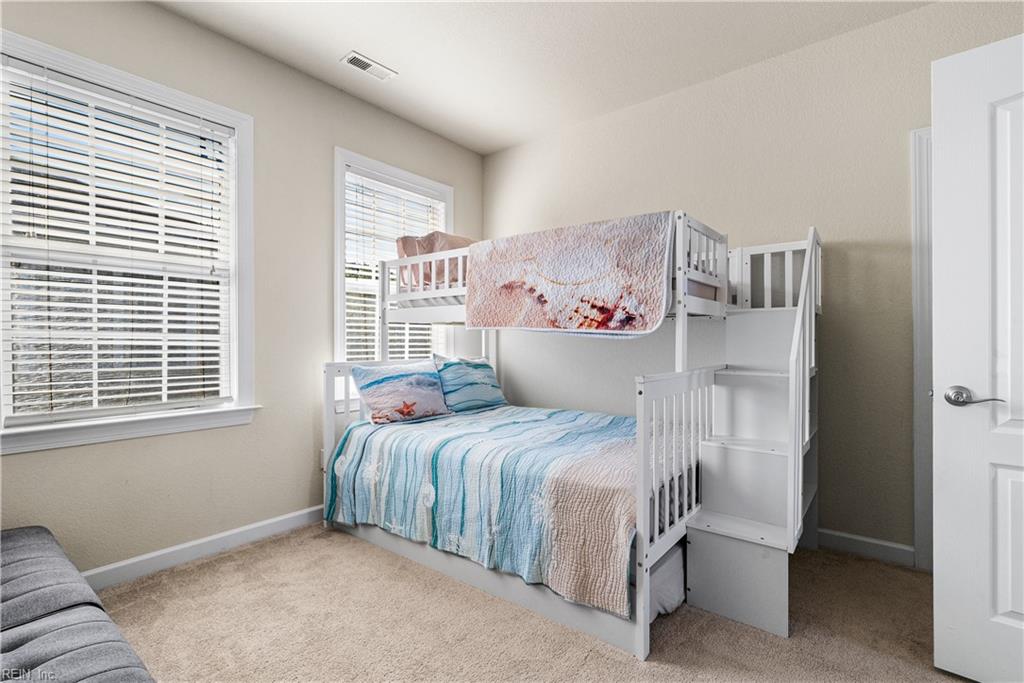 Bedroom with a white bunk bed, blue-and-white bedding, and windows with white blinds.