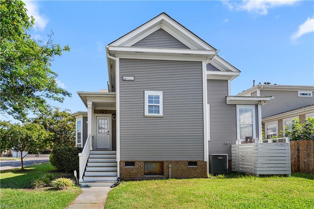 Gray-sided house with white trim, entry stairs, and a fenced patio beside the lawn.
