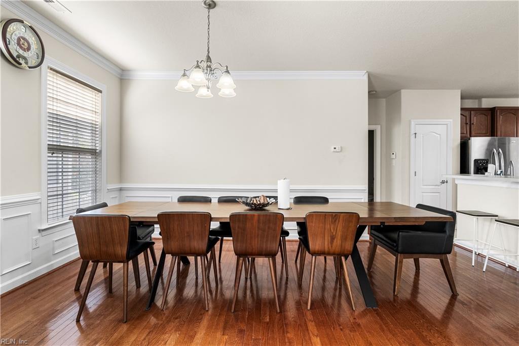 Dining room with a long wooden table, matching chairs, hardwood floors, and a chandelier.