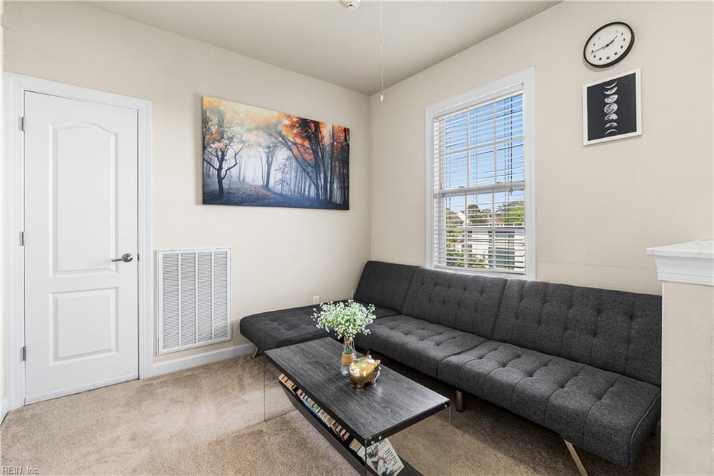 Furnished living room with a dark gray sectional, black coffee table, and window with blinds.