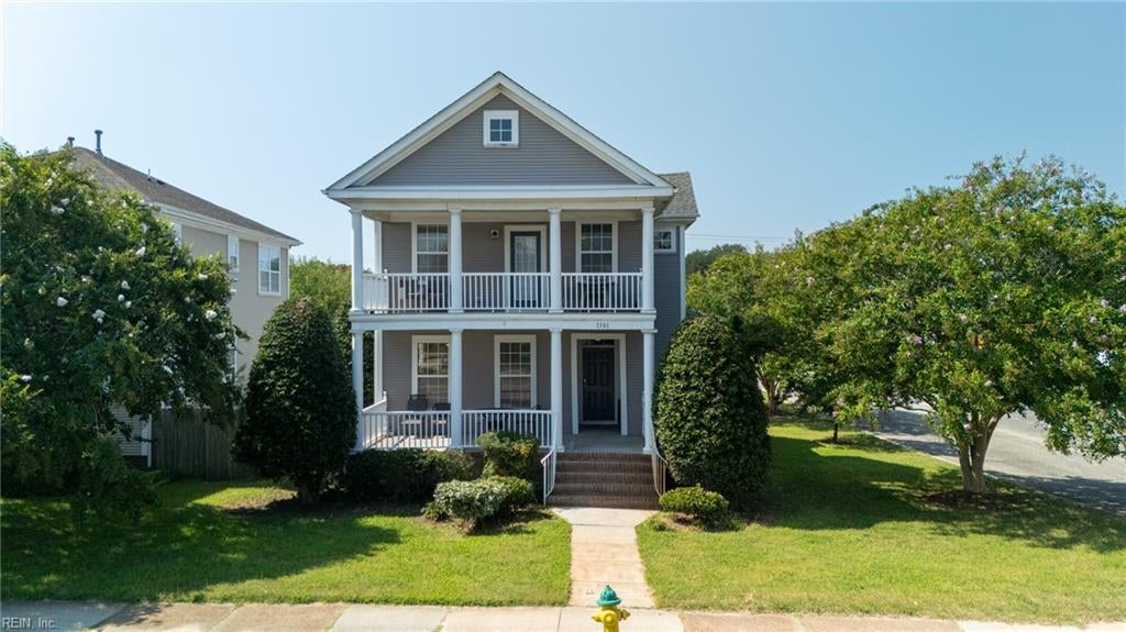Gray two-story house with white double porches, front walkway, and landscaped lawn.