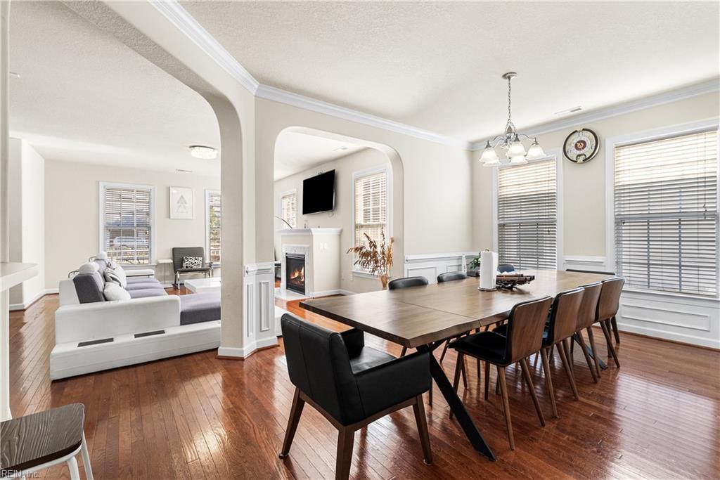 Dining room with a large wood table and chairs, adjoining a living room with a fireplace.