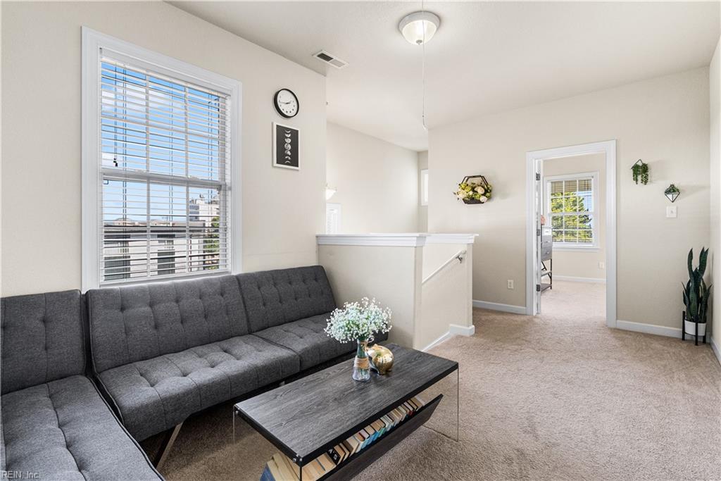 Living room with a dark gray sectional sofa, coffee table, and large window with blinds.