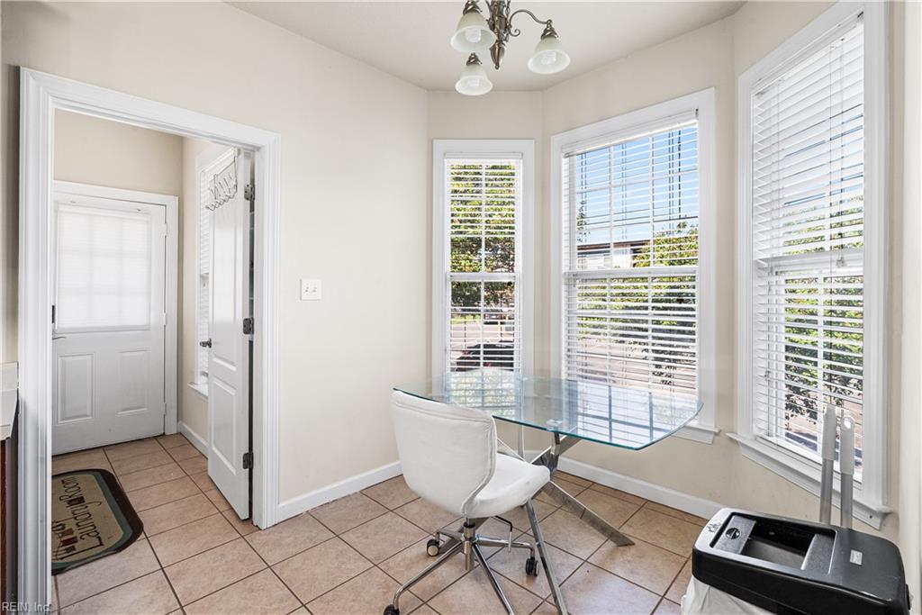 Bright breakfast area with a glass table and chair beside three large windows.
