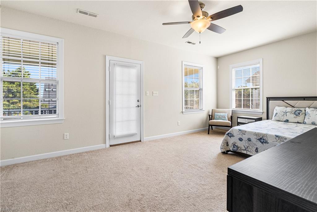Furnished bedroom with beige carpet, a ceiling fan, and a bed with blue patterned bedding.