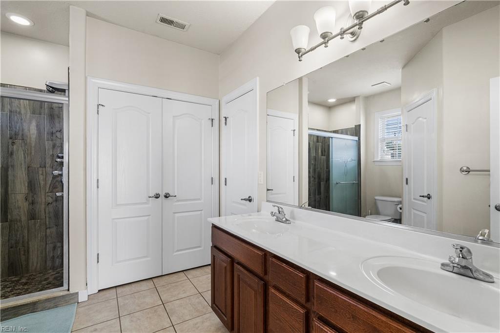 Bathroom with a long double-sink vanity and glass shower with dark tile.