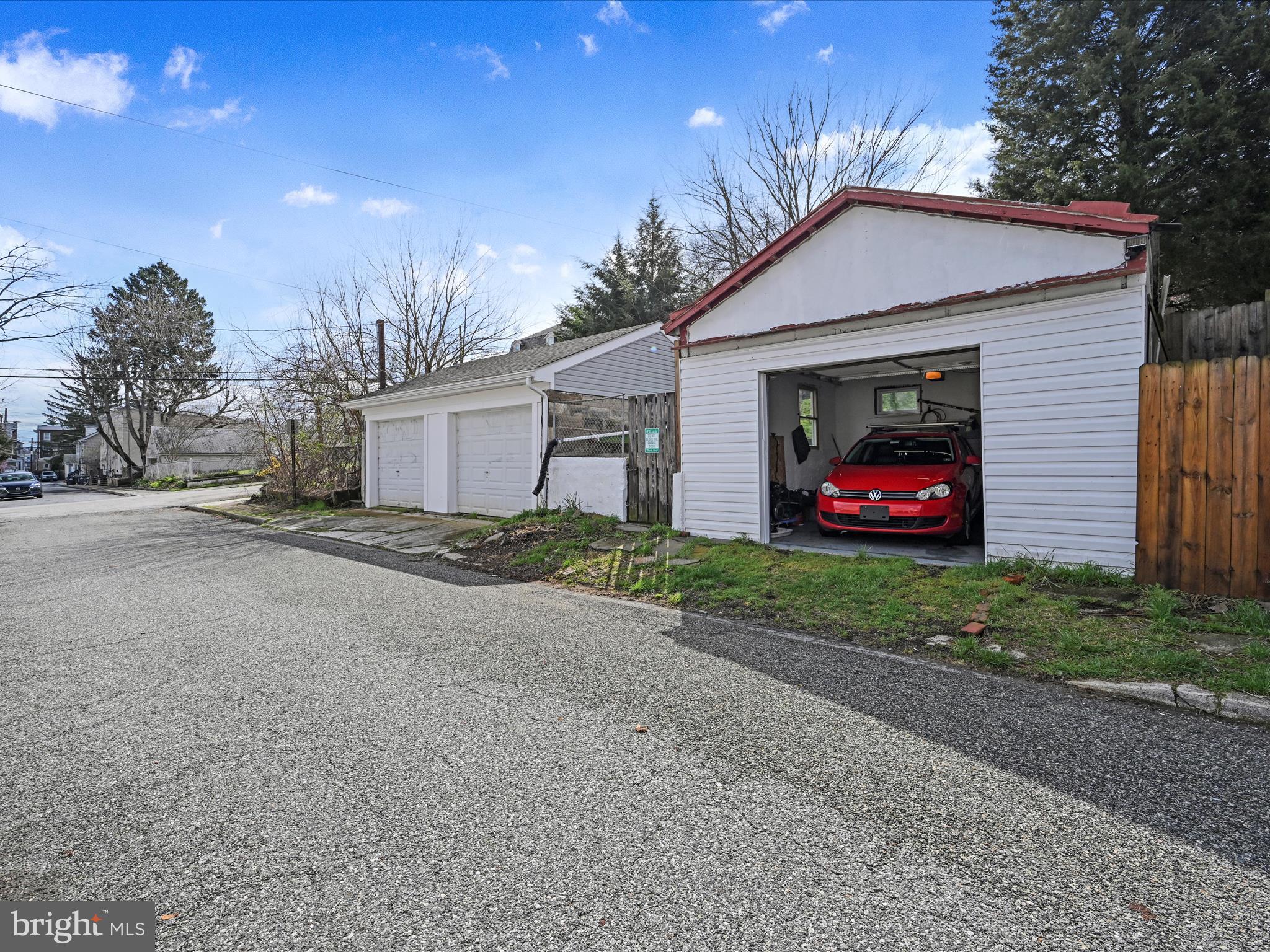 White detached garage with red roof trim and an open door showing a red car.