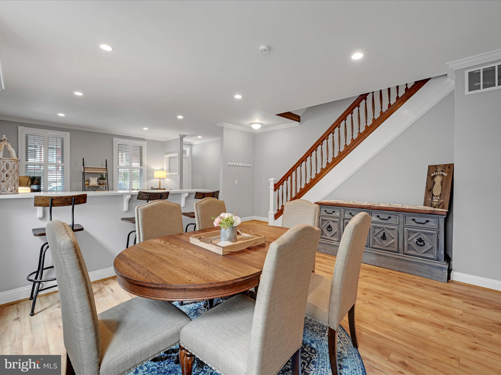 Dining area with a round wooden table, breakfast bar, and staircase with a wooden railing.