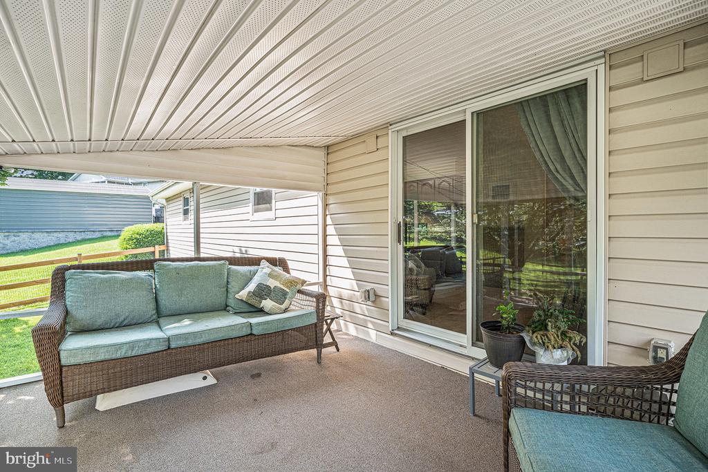 Covered patio with wicker seating and sliding glass doors.