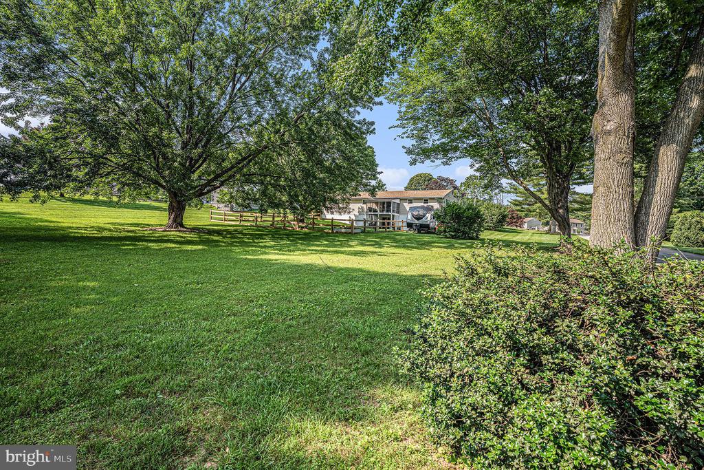 House beyond a broad lawn, framed by mature trees and shrubs.
