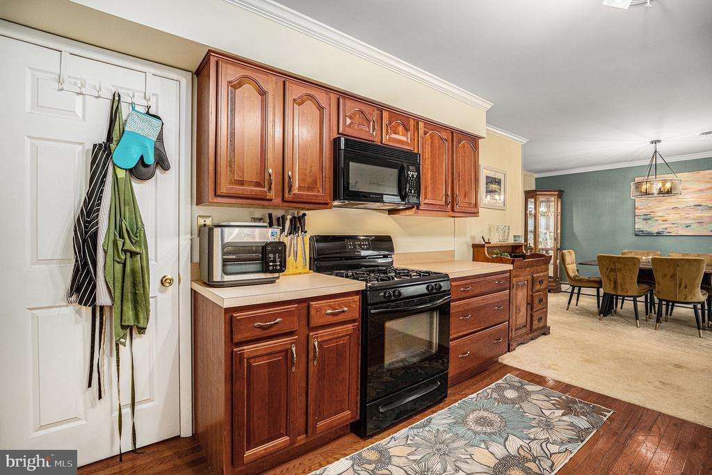 Kitchen with reddish-brown wood cabinets, black gas range, and an adjoining dining area.