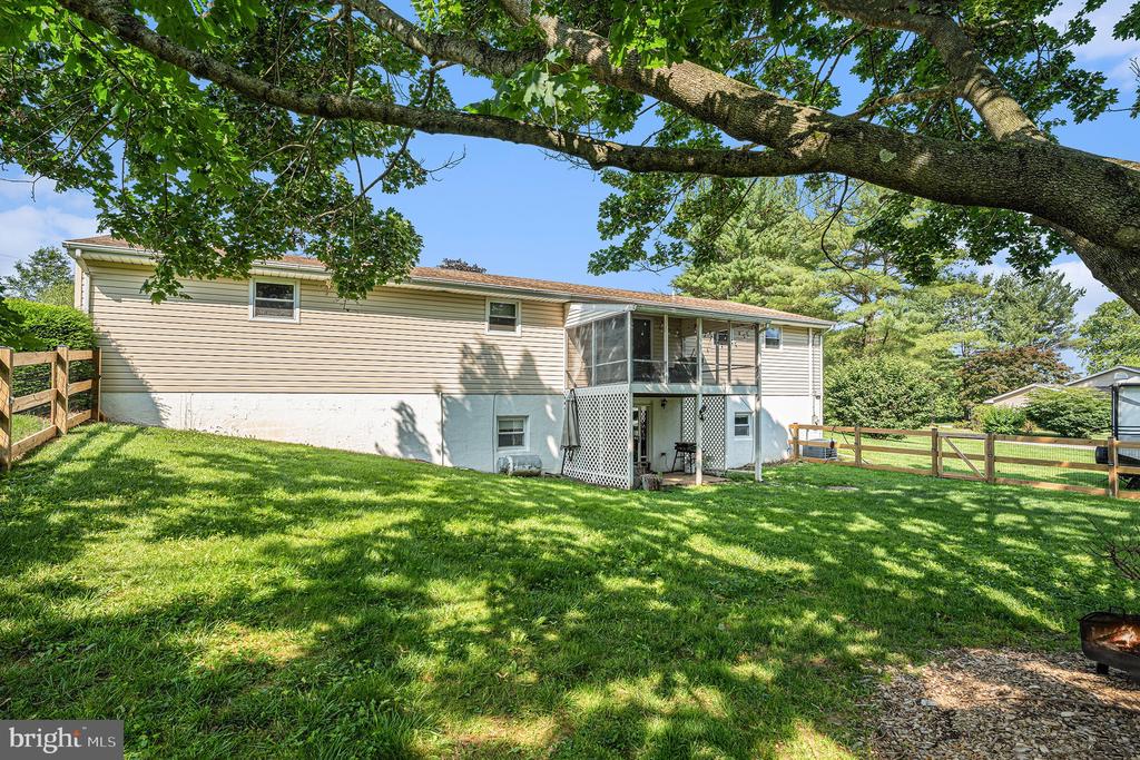House rear with screened porch and deck overlooking a shaded, fenced lawn.