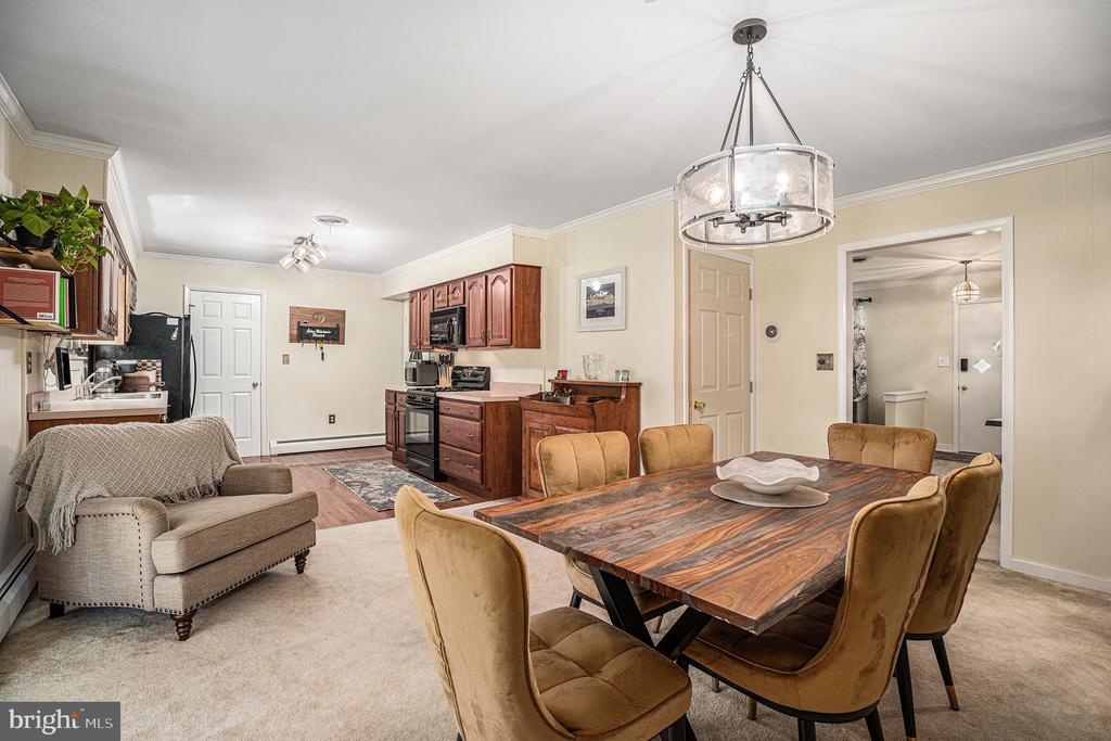 Open dining and kitchen area with a wood table, upholstered chairs, and dark wood cabinets.