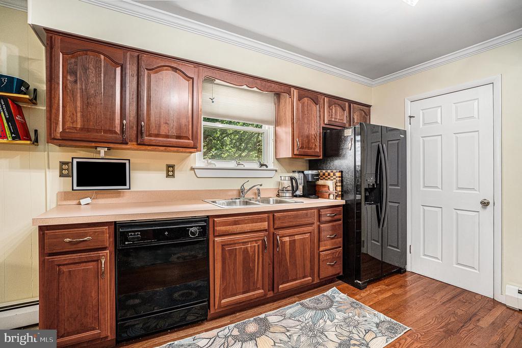 Kitchen with reddish-brown cabinets, a double-basin sink beneath a window, and black appliances.