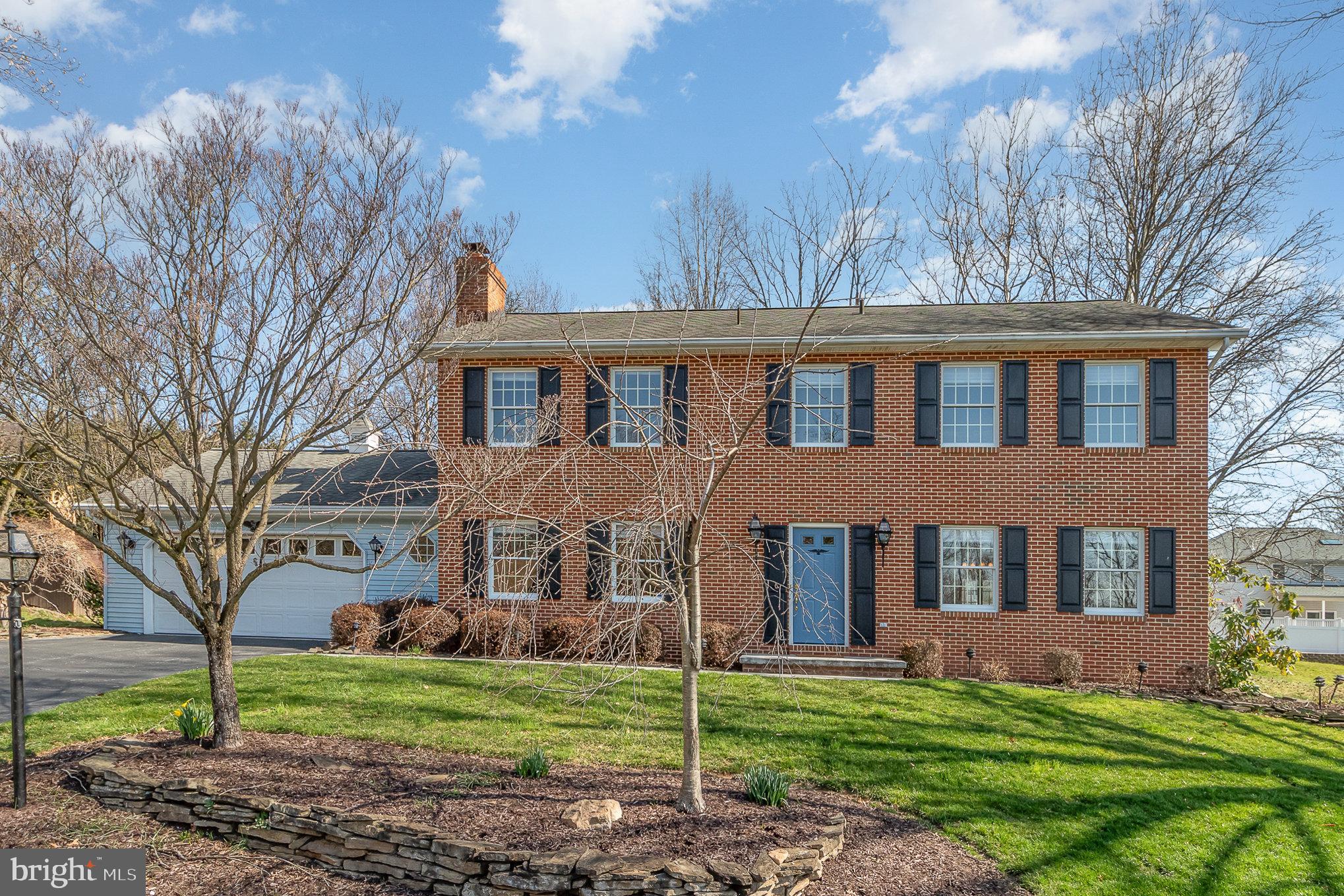 Two-story brick house with black shutters, a blue front door, and an attached white garage.
