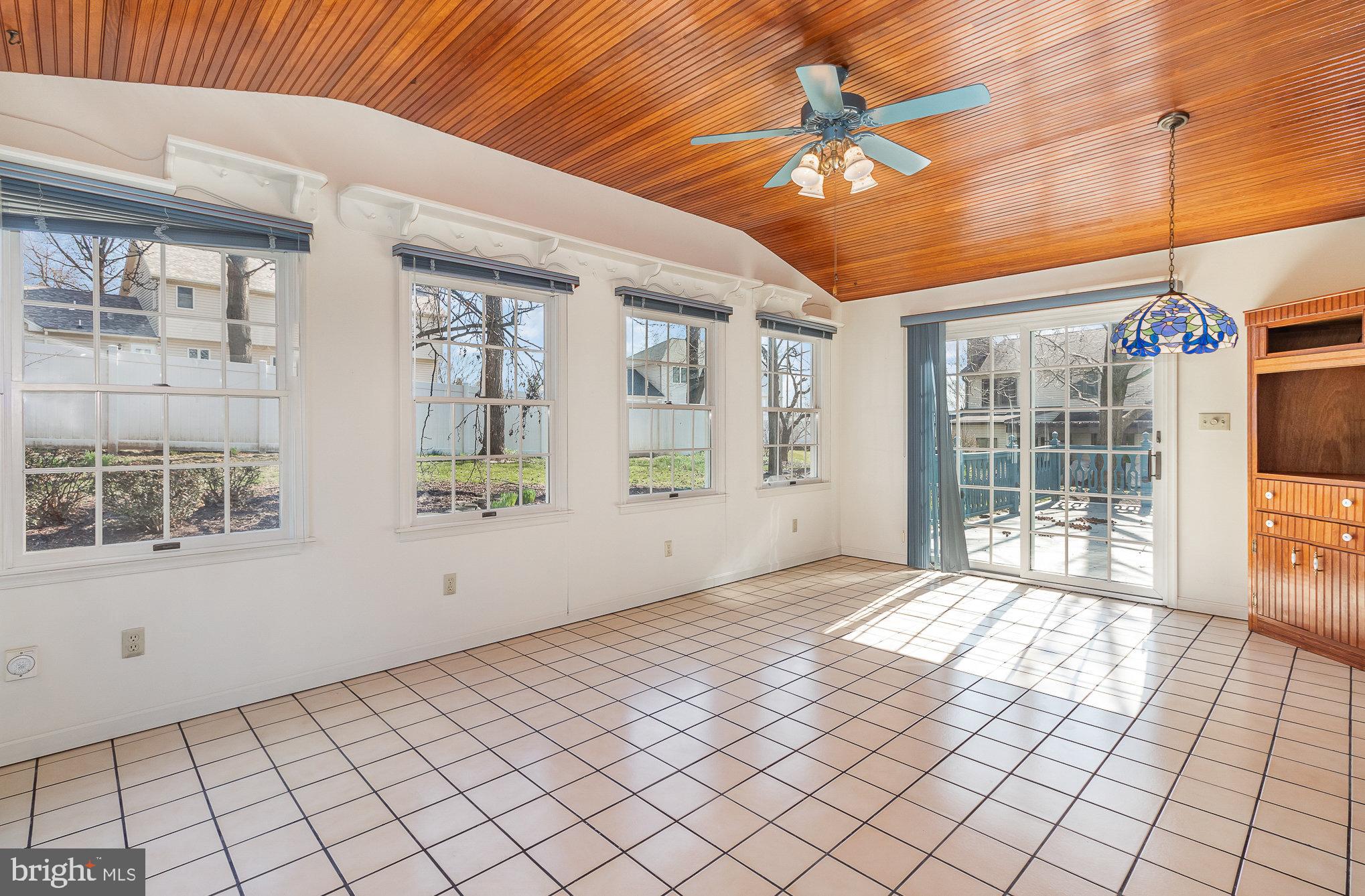 Sunroom with a vaulted wood ceiling, tiled floor, and sliding glass doors to a deck