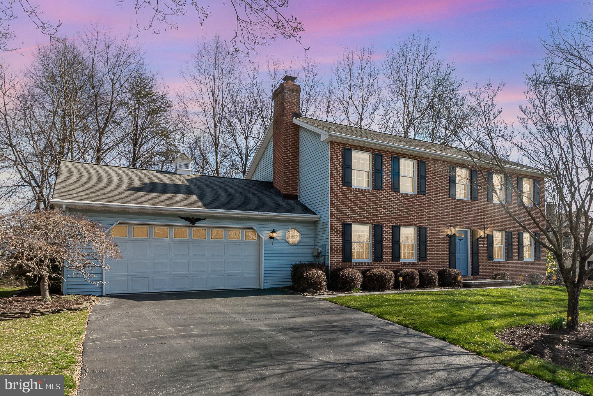 Two-story brick house with blue siding, an attached garage, and a pink evening sky.