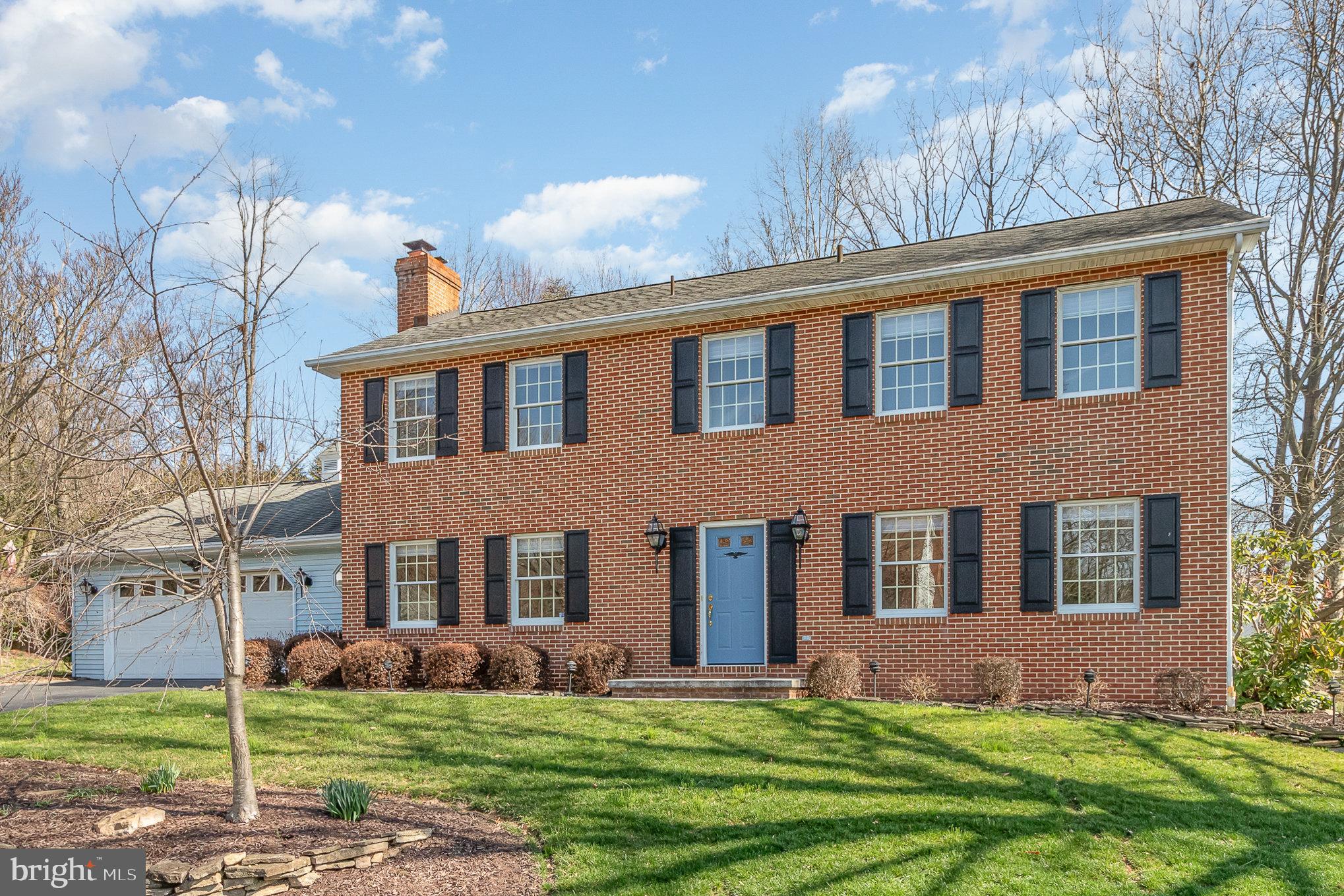 Two-story brick house with black shutters, a blue front door, and an attached white garage.