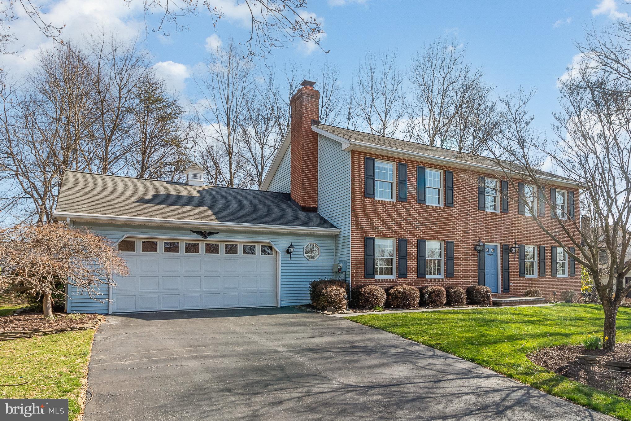 Two-story brick home with blue siding, a blue front door, and an attached two-car garage.